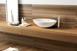 Badezimmer mit Fliesen in Holzoptik und weißen Waschbecken aus Keramik