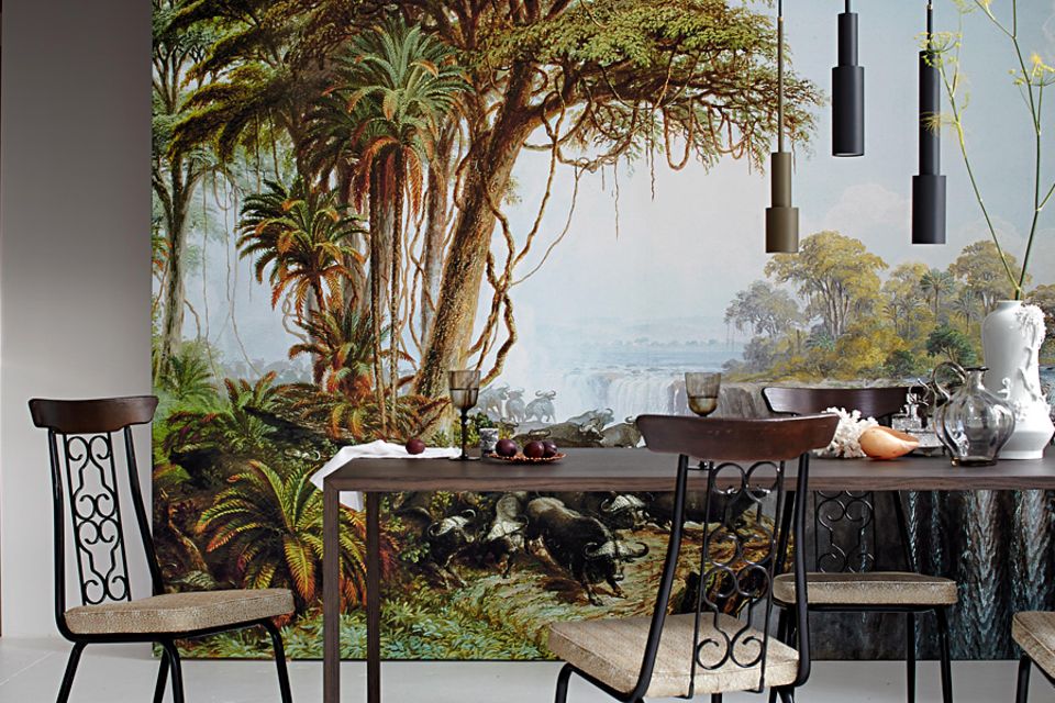 Offene Wohnküche mit großer Fototapete im Dschungel-Look an der Wand, davor steht ein Esstisch mit vier Stühlen
