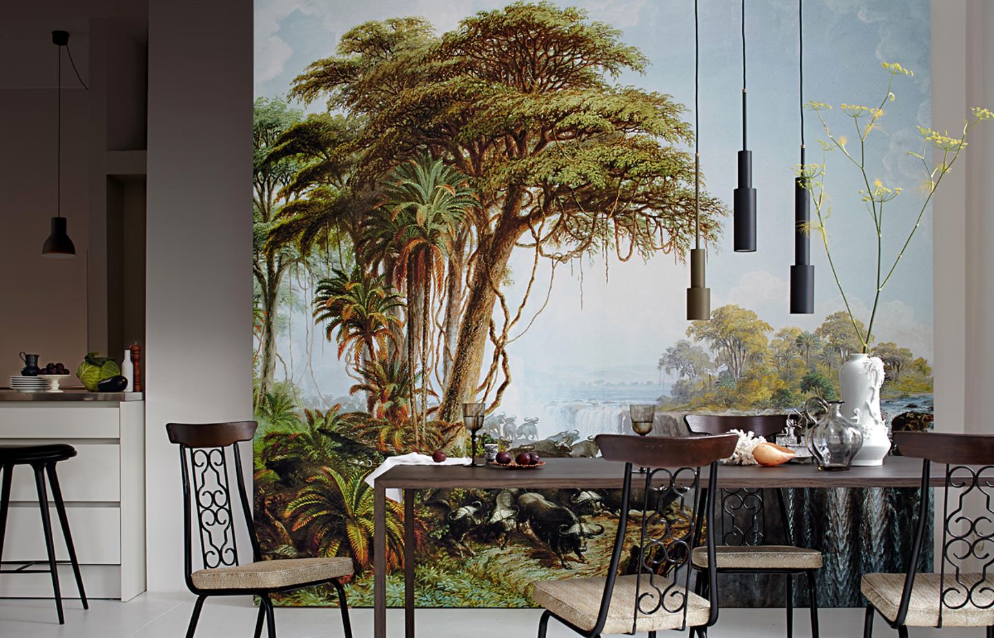 Offene Wohnküche mit großer Fototapete im Dschungel-Look an der Wand, davor steht ein Esstisch mit vier Stühlen