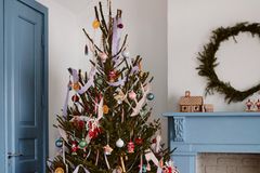 Bunt behangener Weihnachtsbaum neben blauem Kamin