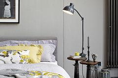 Ein Schlafzimmer in Grau mit Textilien in Senfgelb