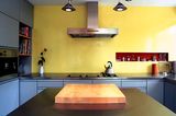 Klar gegliederte Küche mit gelber Wand