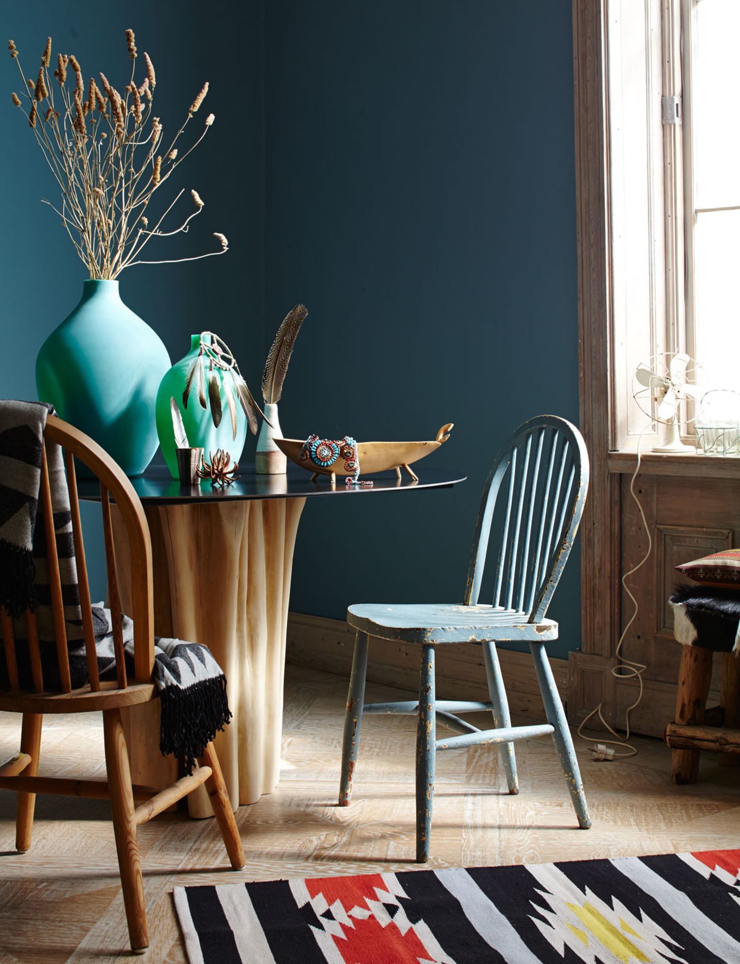 Wandfarbe in Petrol, runder Esstisch und Stühle aus Holz