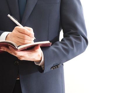 Mann im Anzug macht sich Notizen