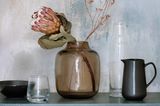 Braune Glasvase mit exotischer Blüte
