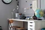 Homeoffice mit altem Schulstuhl und Globus vor grauer Wand