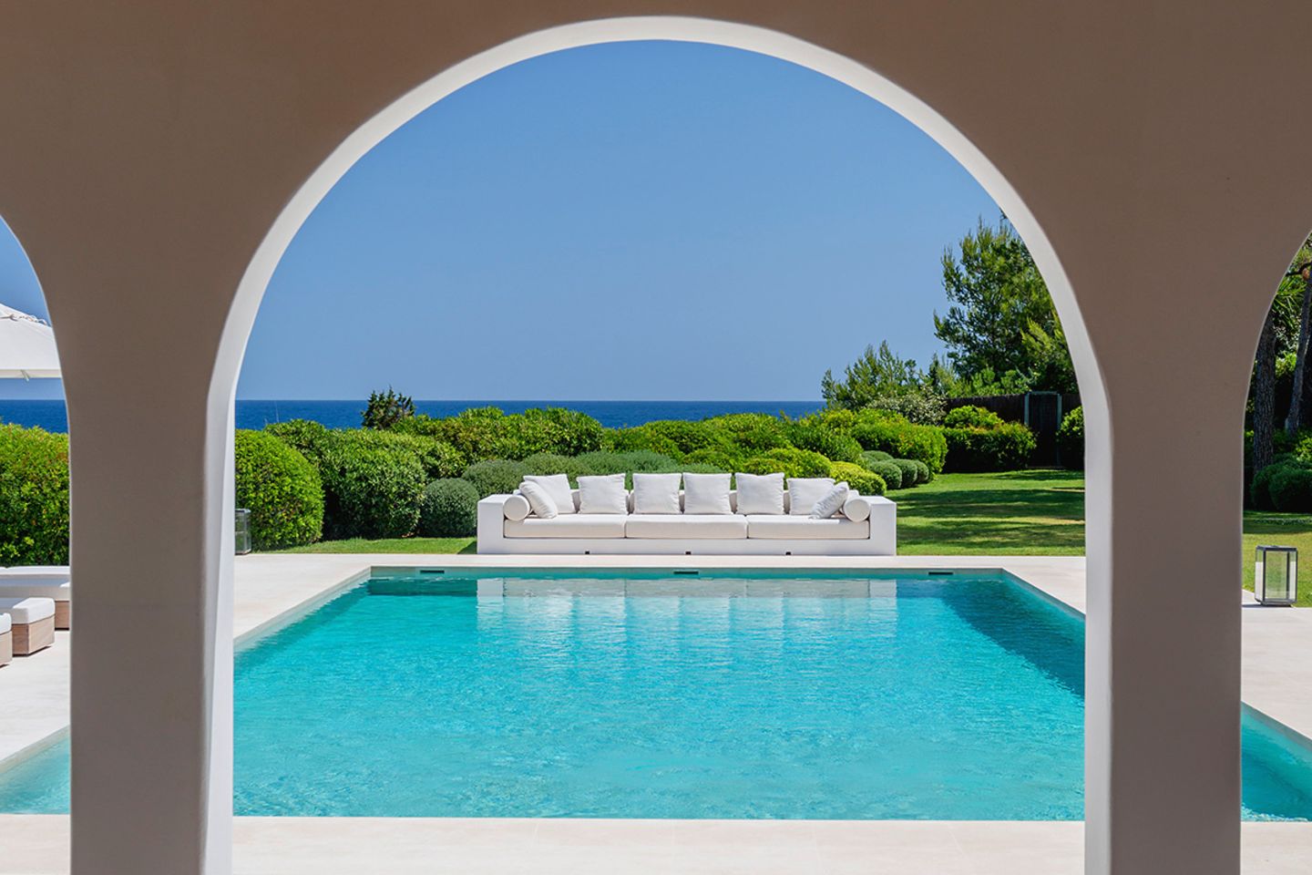 Ibiza: Blick durch die Arkaden auf einen Pool mit langem Outdoorsofa