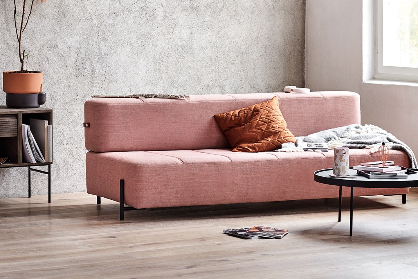 Rosafarbenes modernes Schlafsofa mit geradlinigem, minimalistischem Design von Northern mit braunem Kissen und Überwurf