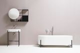 Puristisch anmutendes Badezimmer mit einer freistehenden Badewanne, Waschtisch und Spiegel vor einer dezent rosafarbenen Wand