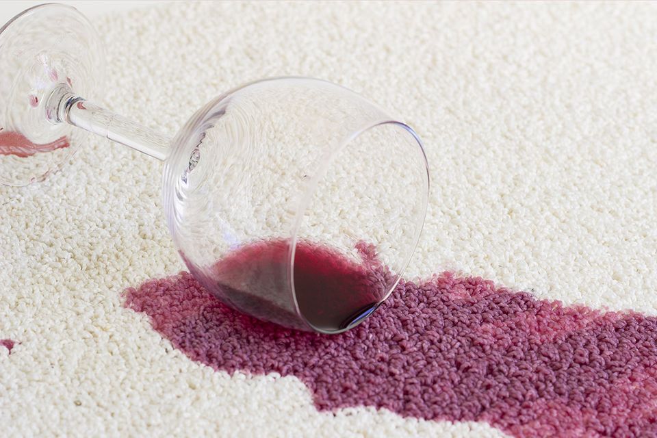 Umgekipptes Rotweinglas auf dem Teppich