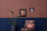 Sessel und Zimmerpflanze vor tapezierter Wand. Die Tapete: "Raffia Weave" mit Raffiagewebe auf Vliesträger von Zimmer+Rohde