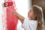 Ein Mädchen streicht eine Wand rot