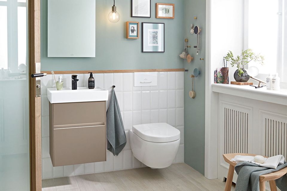 Gäste-WC mit salbeifarbenen Wänden und weißer Badezimmerkeramik, Bildern und Pflanzen