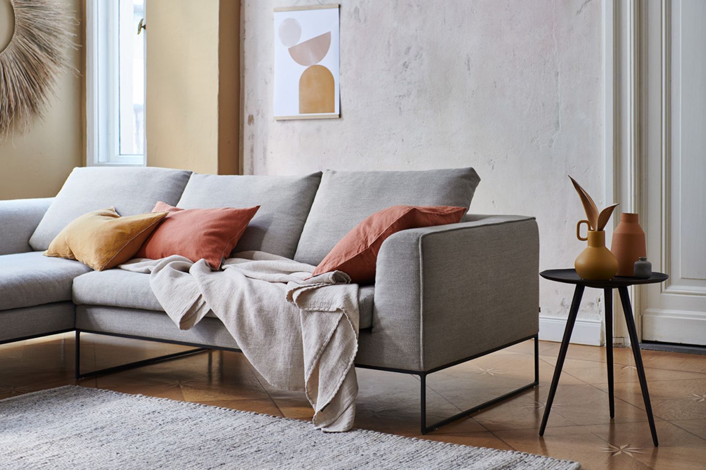 Soft Minimalism: Graues Sofa mit warmen Farben dekorieren