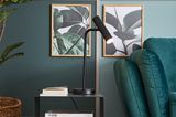Tischleuchte "Stina" aus der SCHÖNER WOHNEN-Kollektion in Schwarz in einem Wohnzimmer in Grüntönen