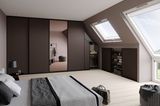 Maßgeschneidertes Innensystem von Raumplus in dunklem Braun mit Spiegelelement für ein Schlafzimmer mit Dachschräge