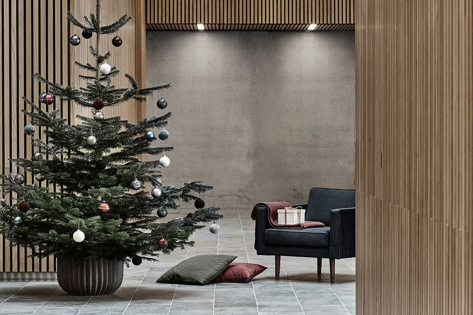 Geschmückter Weihnachtsbaum in einem mit Holz verkleideten Raum mit sehr hohen Decken