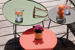 Verschiedene Beistelltische und Outdoor-Leuchten von Fermob auf einer Terrasse