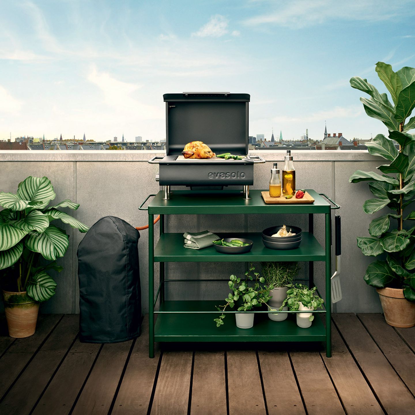 Gasgrill "Box" von Eva Solo auf einem grünen, dreistöckigen Tischchen auf einer Terrasse