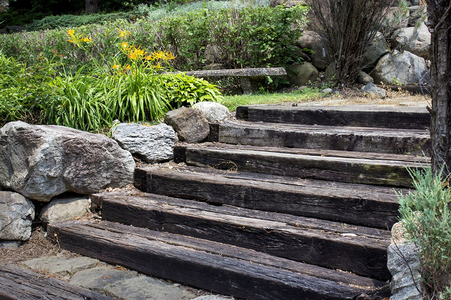 Gartentreppe aus Holzbohlen im Sommer.