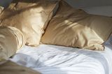 Aufgeschlagene Bettwäsche "Strimma" von Alvalinen an einem sonnigen Morgen