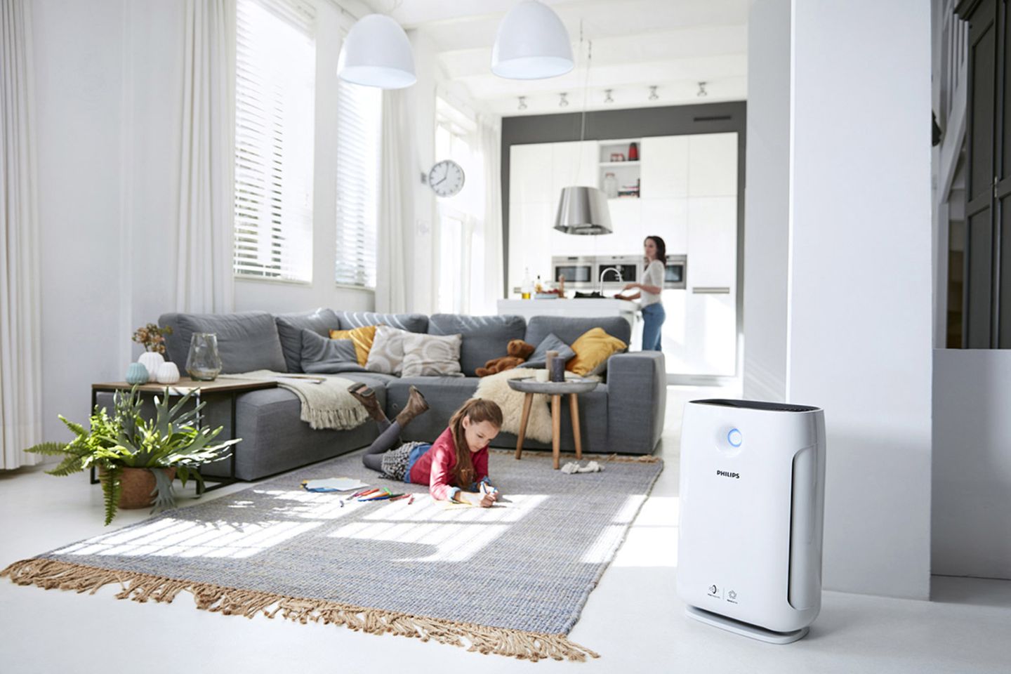 Luftreiniger "AC2889" von Philips in einem Wohnzimmer mit einem jungen Mädchen auf einem Teppich und der Mutter im Hintergrund