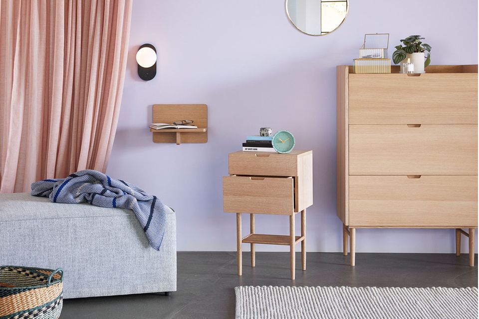 Schlafzimmer mit Wandfarbe in Flieder und hellem Holz