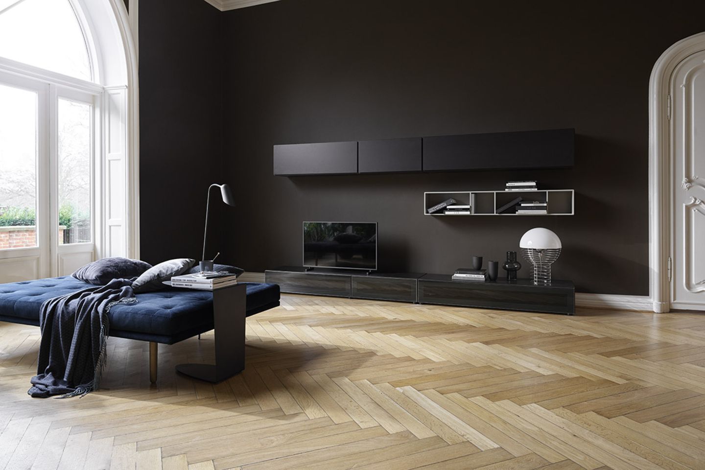 Tagesbett "Fusion" von BoConcept in einem geräumigen Wohnzimmer mit Parkettboden und schwarzer Wand