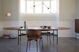 Ovaler Massivholztisch in einem eleganten, reduziert eingerichteten Ambiente