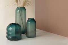 Grünfarbene Glasvasen mit Gräsern dekoriert