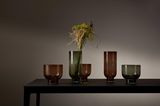 Braune und grüne Glasvasen auf Holztisch dunkle Stimmung