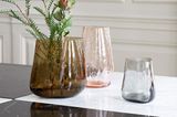 Verschieden farbige Glasvasen auf Marmortisch mit Blumendeko