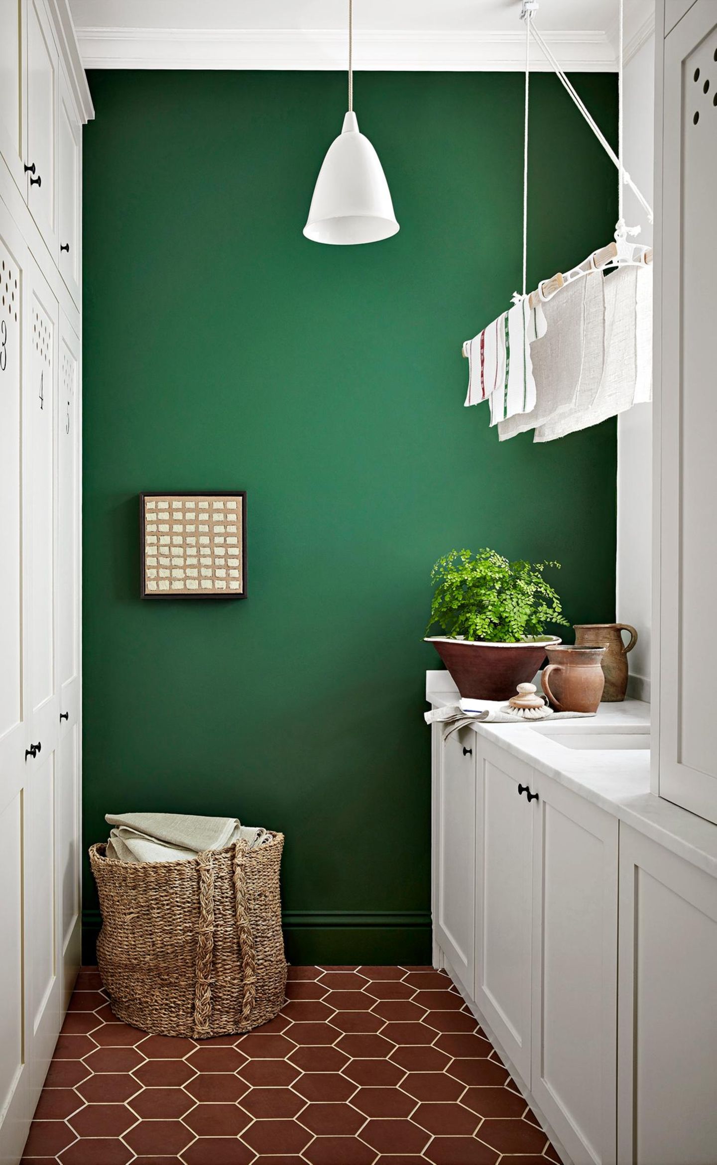 Weiße Küche mit hängendem Wäscheständer vor dunkelgrüner Wand