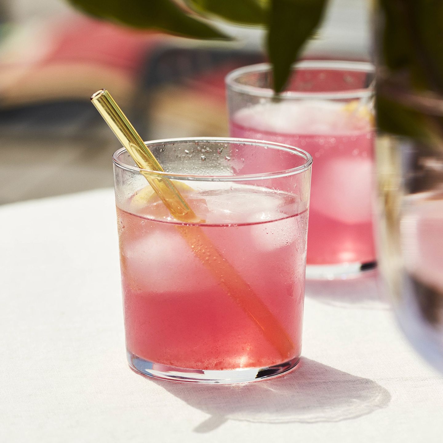 Mittelgroßes Glas mit Pink leuchtendem Cocktail und einem gelben Glasstrohhalm