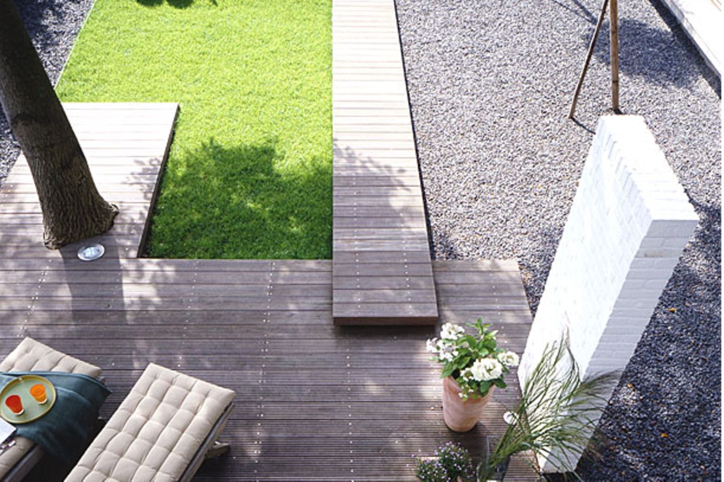 Terrasse aus Holz mit Kiesbeet und kleiner Grünfläche