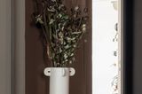 Bodenvase "Calli" aus der "Muses"-Kollektion von Ferm Living mit langstieligen Blumen auf einem Beistelltisch