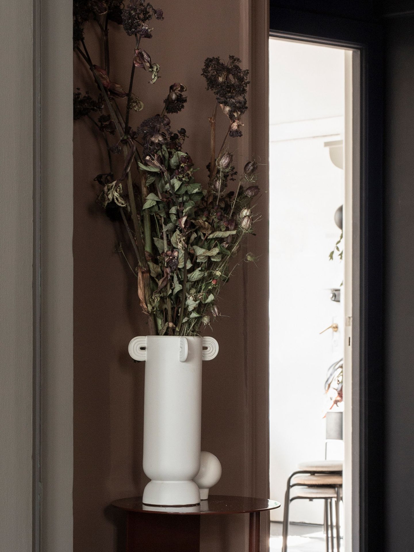 Bodenvase "Calli" aus der "Muses"-Kollektion von Ferm Living mit langstieligen Blumen auf einem Beistelltisch