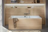 Badezimmer mit Holzverkleidung an Wanne und Wand