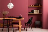 Esszimmer mit roter Wandfarbe und Möbeln in Schwarz und Holz