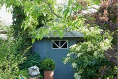 Sichtachse im Schattengarten auf ein blaues Gartenhaus