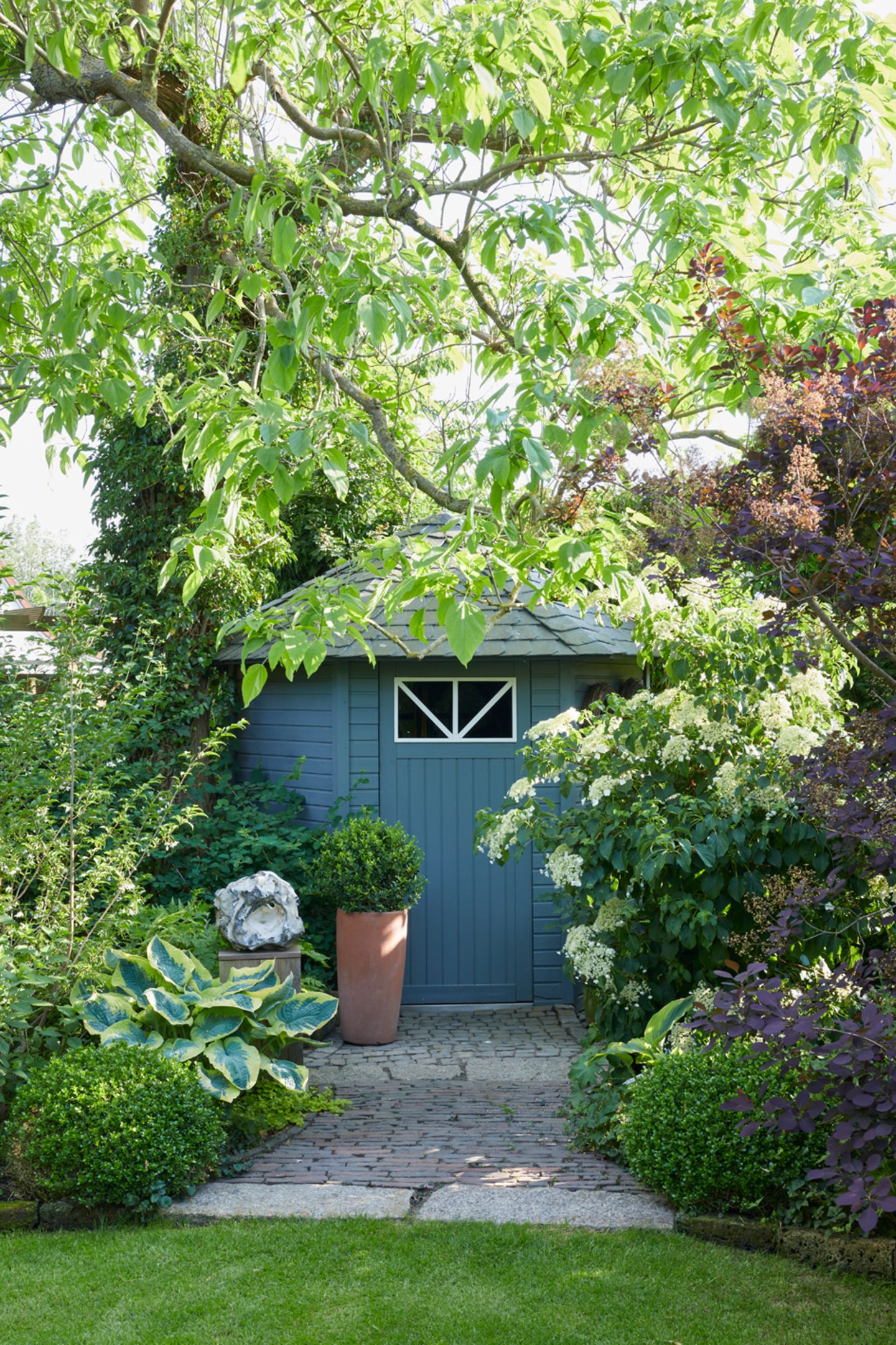 Sichtachse im Schattengarten auf ein blaues Gartenhaus