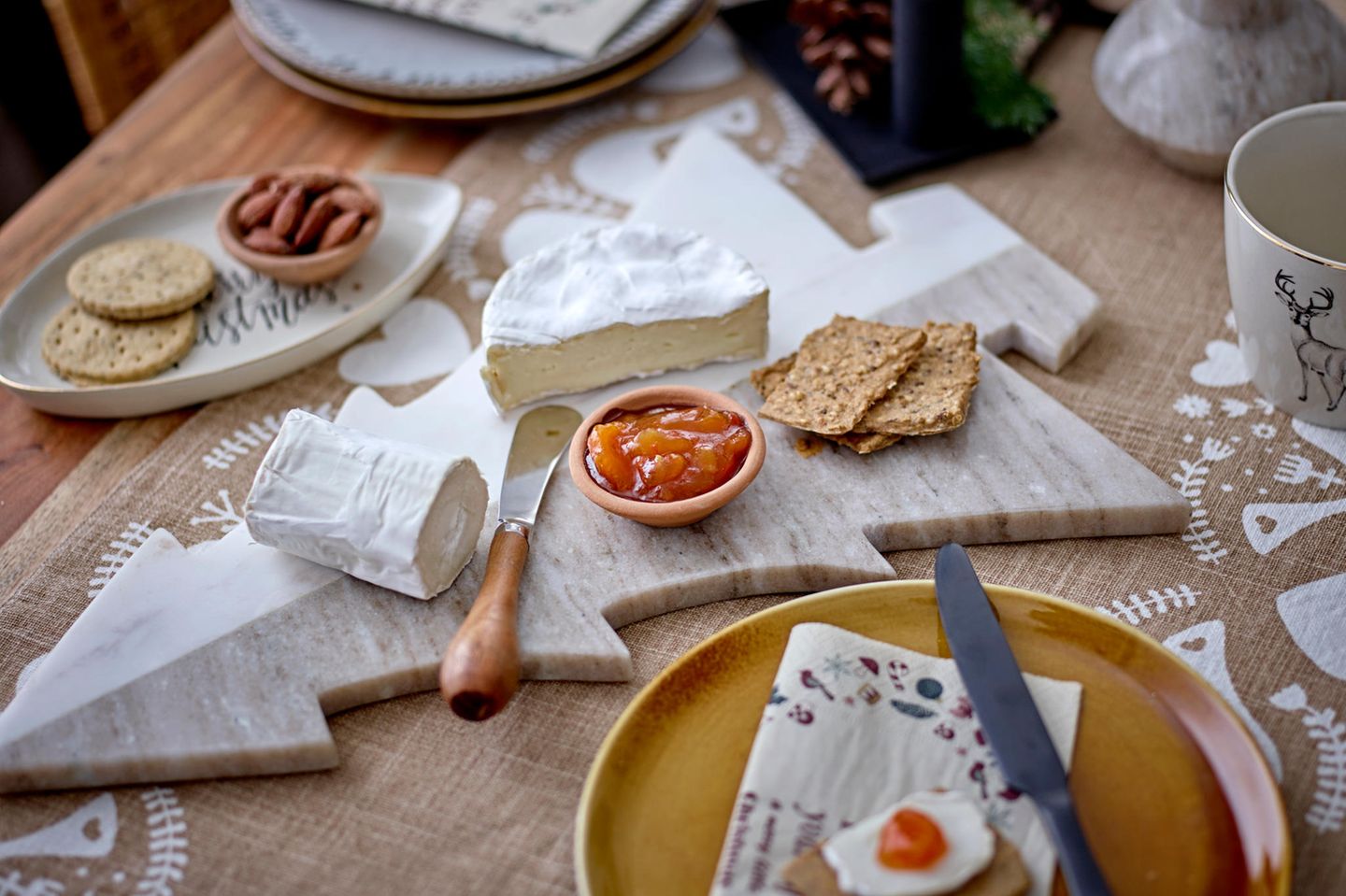 Marmor-Servierplatte mit Käse, Chutney auf einem hell eingedeckten Tisch