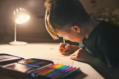 Malendes Kind am Schreibtisch mit heller Schreibtischbeleuchtung