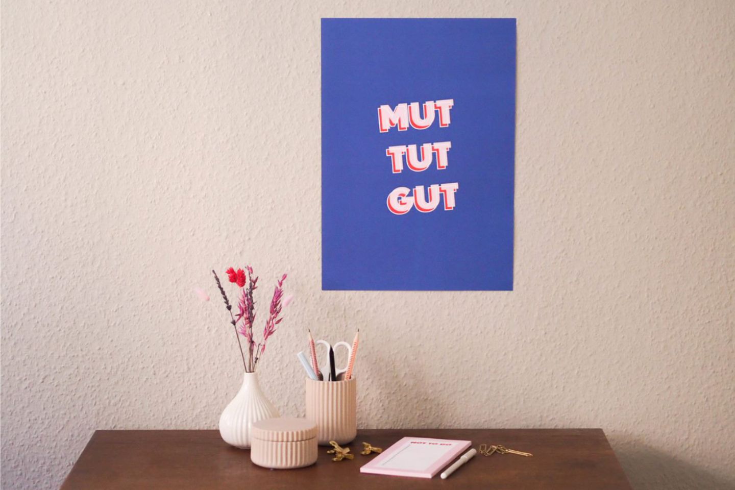 Poster mit Spruch "Mut tut gut" über dem Schreibtisch