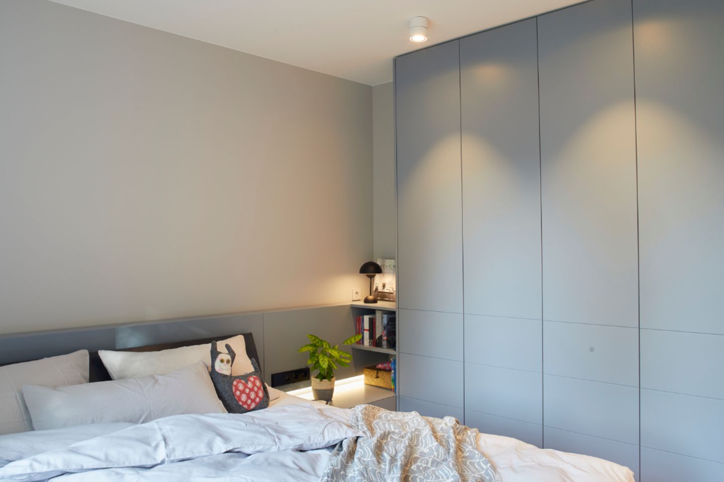 Elternschlafzimmer mit graublauem Einbauschrank und grauer Wand