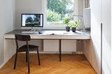 Arbeitszimmer mit Schreibtisch vor dem Fenster und Einbauschrank