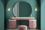 Pinker Schminktisch mit pinkem Hocker und großem runden Spiegel vor einer grünen Wand