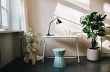 Klappbarer Schreibtisch an Wand mit Tischlampe und Hocker