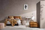 Cognacfarbenes Schlafsofa vor grauer Wand
