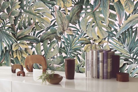 Dezent dekoriertes Sideboard mit Tapete im Dschungel-Look im Hintergrund
